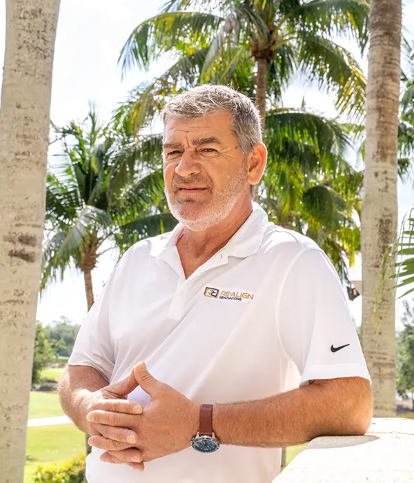Photo of president and design specialist Mike Butar, standing outside a country club surrounded by palm trees.